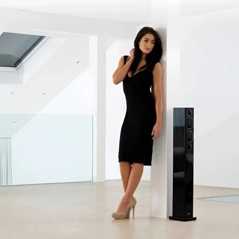 Frau in schwarzem Kleid und High Heels neben Monitor Audio Radius 270 mit Bass Treibern