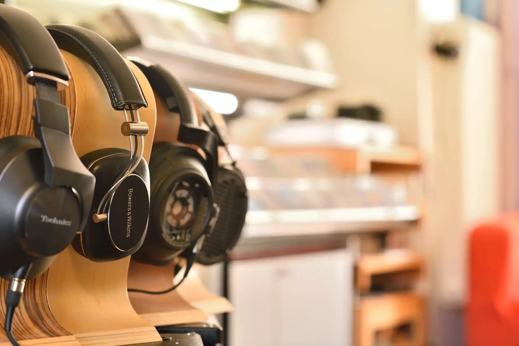 Mehrere Over-Ear-Kopfhörer, die auf Holzständern präsentiert werden.