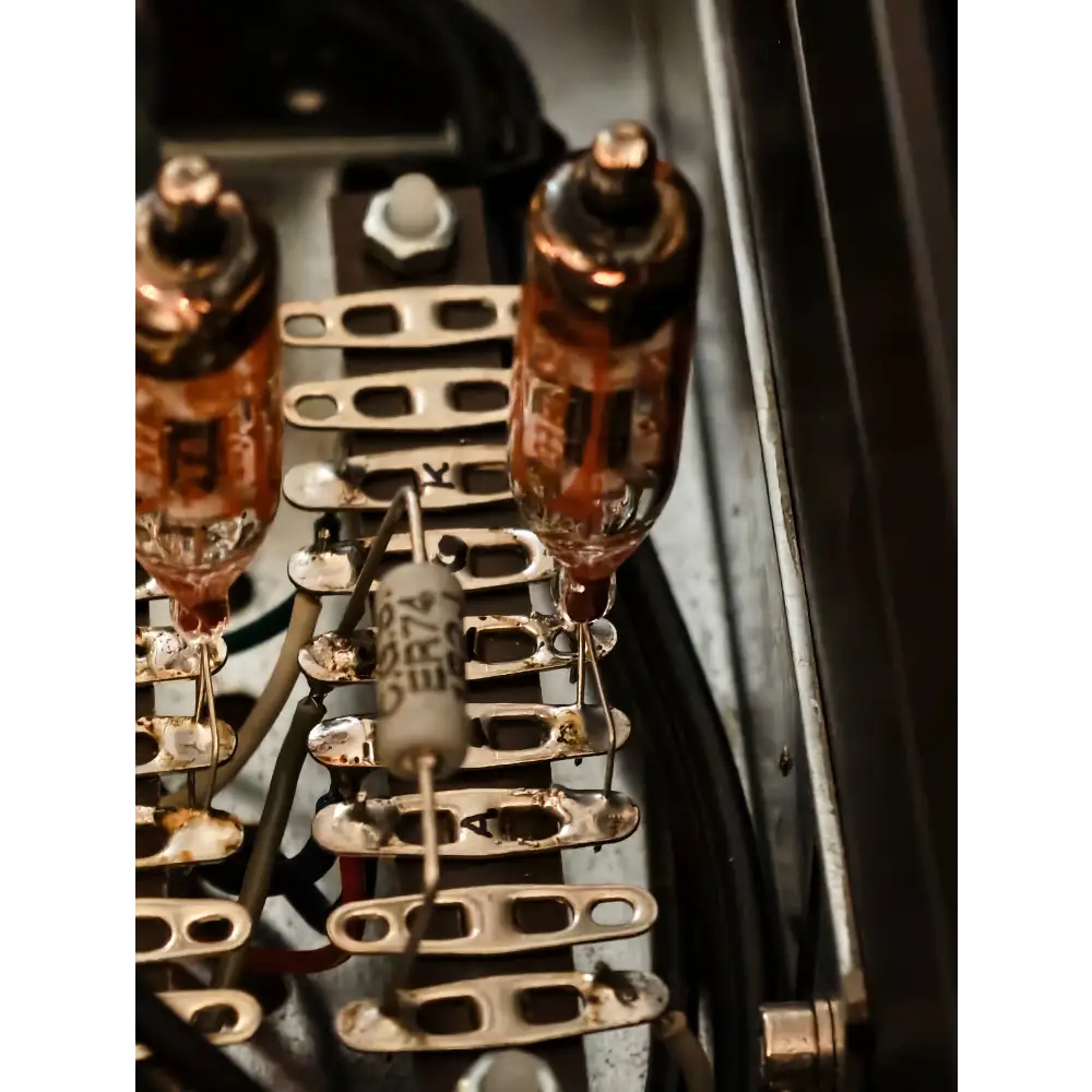 Zwei vintage-vakuumröhren aus bernsteinfarbenem glas mit messingfarbenen fuß montiert auf metallgestell neben zylindrischem cer72 kondensator bei ayon audio highend schaltung rohrenvorstufe othello line secondhand mit fb