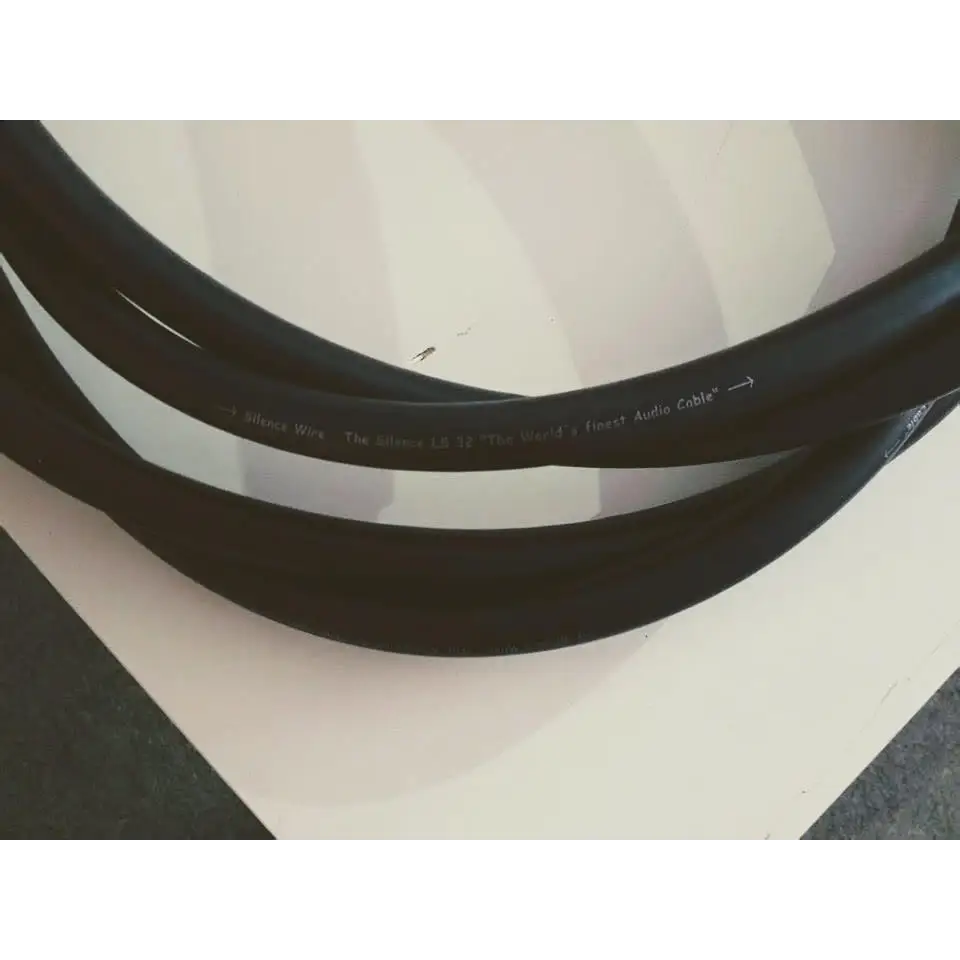 Schwarzes Audiokabel coiled auf weißer Oberfläche mit WBT Nextgen Bananensteckern